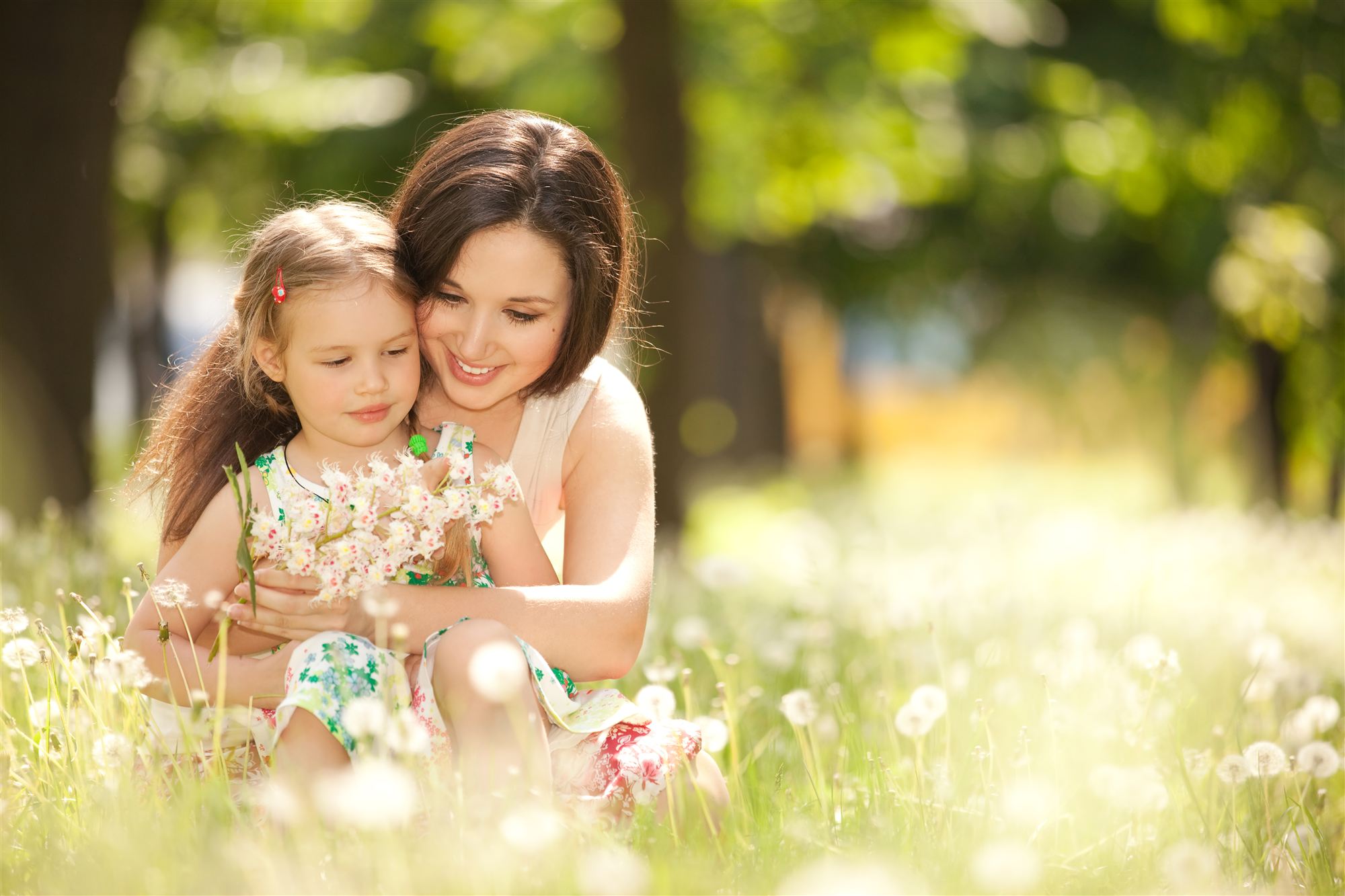 A mother and her daughter holding wildflowers in a sunny meadow